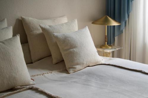 a bed with white pillows and a table with a lamp at SJ Apartment in Aarhus