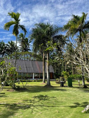 a resort with palm trees and a building in the background at Tambua Sands Beach Resort in Korotogo
