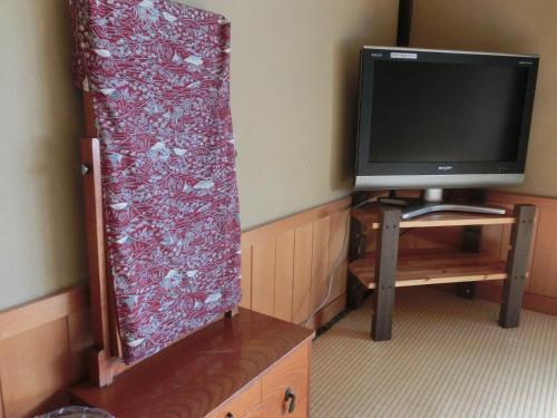 a room with a tv and a curtain next to a table at Tajimaya in Nakatsugawa