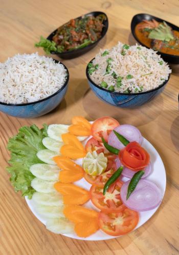 a plate of food with rice and vegetables on a table at The Lake Palm Hotel in Kolkata