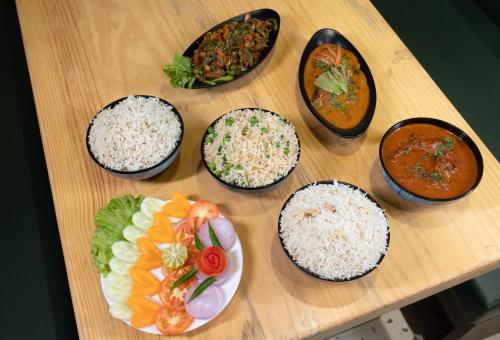 a table with bowls of rice and different types of food at The Lake Palm Hotel in Kolkata