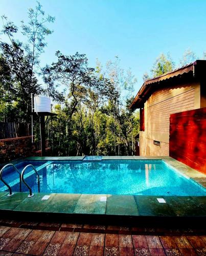 a swimming pool in front of a house at Sereno Barn Eco Stay Chikmagalur in Chikmagalūr