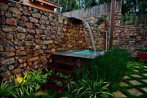 a stone wall with a table and a water fountain at Sereno Barn Eco Stay Chikmagalur in Chikmagalūr