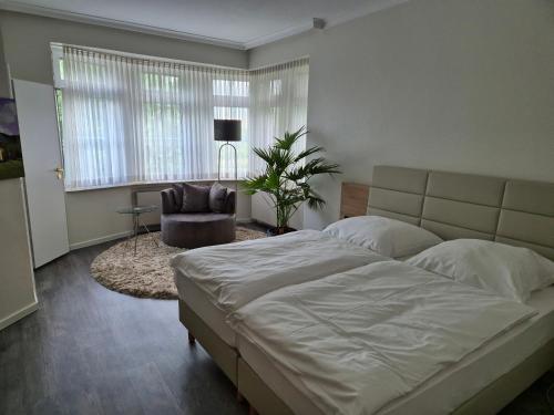a bedroom with a large bed and a chair at Hotel am Schlosspark in Bad Bentheim