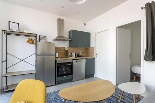 Il comprend une cuisine équipée d'un réfrigérateur, d'une table et de chaises. dans l'établissement DIFY Wilson - Villeurbanne, à Villeurbanne