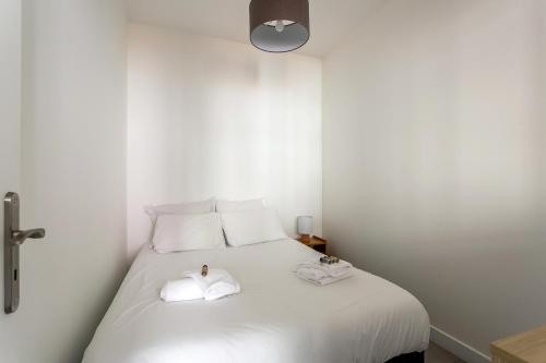 une chambre avec un lit blanc avec deux serviettes dessus dans l'établissement DIFY Wilson - Villeurbanne, à Villeurbanne