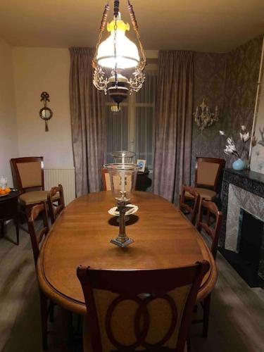 une salle à manger avec une table en bois et un lustre dans l'établissement Sfeervol huis op het platteland, à Mailhac-sur-Benaize