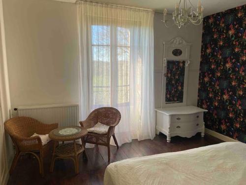 a bedroom with a bed and a table and chairs at Sfeervol huis op het platteland in Mailhac-sur-Benaize