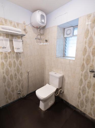 a bathroom with a toilet and a window at The Lake Palm Hotel in Kolkata