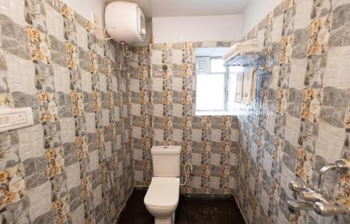 a bathroom with a toilet and a tiled wall at The Lake Palm Hotel in Kolkata