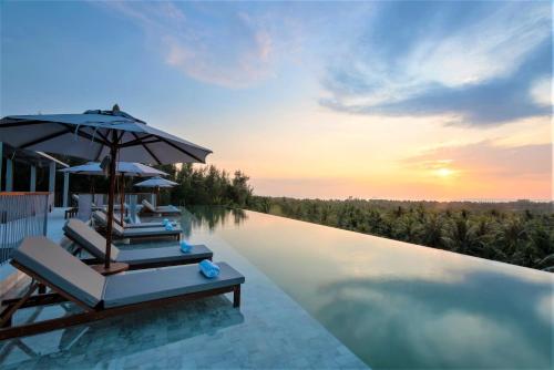 a swimming pool with lounge chairs and an umbrella on a resort at Varivana Resort Koh Phangan, The Centara Collection in Thong Sala