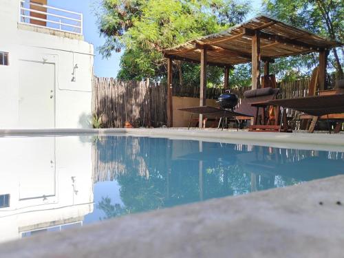 a swimming pool with a wooden gazebo and a picnic table at Luxury House Bacalar in Bacalar