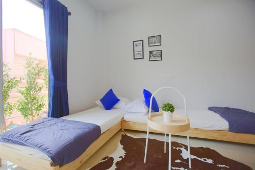 a bedroom with two beds and a table and a window at Trisisters Home by Greenway night market in Hat Yai