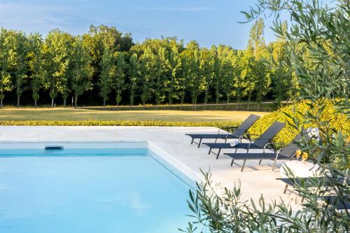 une piscine avec des chaises et des arbres en arrière-plan dans l'établissement Maison avec piscine à la campagne, à Saint-Géry