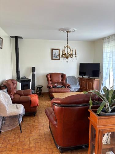 Elle comprend un salon doté d'un mobilier en cuir et d'un lustre. dans l'établissement Gîte l'Hortensia, à Fontenay