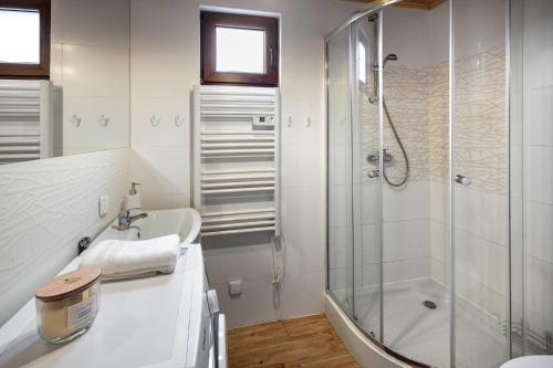 a white bathroom with a shower and a sink at ZACISZE Domek na Kaszubach Brodnica Dolna z balią z jacuzzi na wyłączność w cenie in Brodnica Dolna
