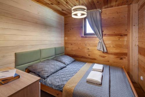 a bedroom with a bed in a wooden cabin at ZACISZE Domek na Kaszubach Brodnica Dolna z balią z jacuzzi na wyłączność w cenie in Brodnica Dolna