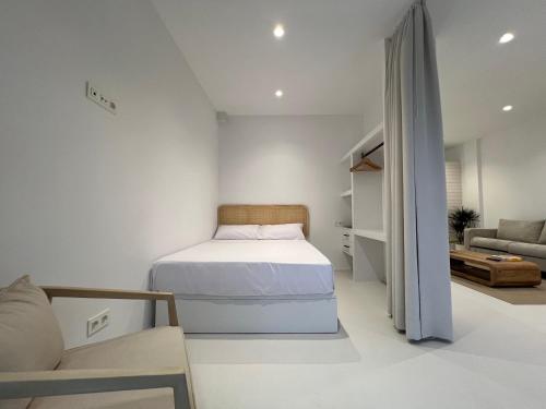 a small white bedroom with a bed and a couch at Ferrol by Miramar Stays in Ferrol