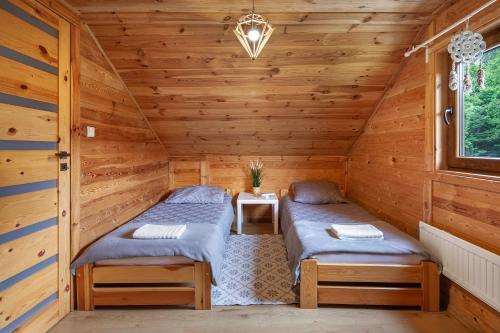 two beds in a room with wooden walls at ZACISZE Domek na Kaszubach Brodnica Dolna z balią z jacuzzi na wyłączność w cenie in Brodnica Dolna