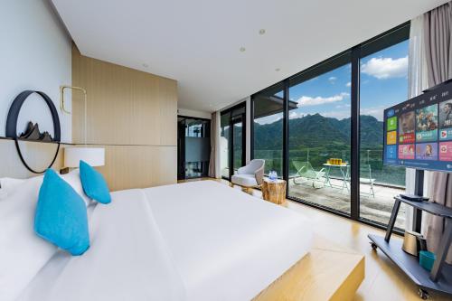 a bedroom with a large bed and a large window at XMAN Sunrise Peaks Resort--Free Pick-up in Zhangjiajie