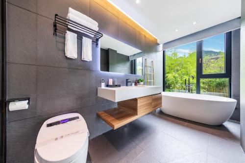 a bathroom with a tub and a toilet and a sink at XMAN Sunrise Peaks Resort--Free Pick-up in Zhangjiajie