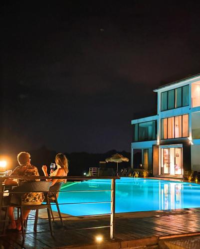 a couple sitting at a table next to a swimming pool at night at XMAN Sunrise Peaks Resort--Free Pick-up in Zhangjiajie