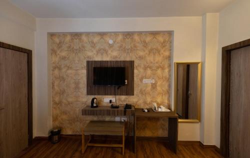 a room with a desk and a television on a wall at The Lake Palm Hotel in Kolkata
