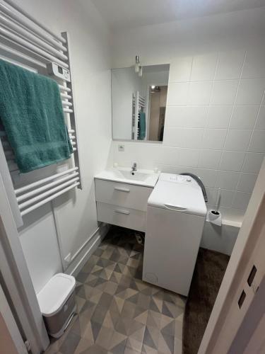 a white bathroom with a toilet and a sink at Charmant studio à Paris in Courbevoie