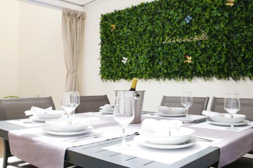 une table à manger avec des assiettes blanches et des verres à vin dans l'établissement Boutique Plaza Catalonia Suites Cornellá, à Cornellà de Llobregat