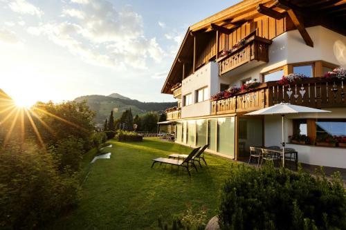 a building with a yard with a bench and the sun at Apartments Burvel in Selva