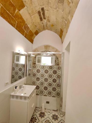 a bathroom with a sink and a tile wall at La Via della Giudecca in Siracusa
