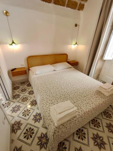 a small bedroom with a bed with two towels on it at La Via della Giudecca in Siracusa