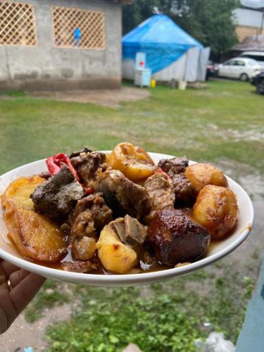a person holding a plate of meat and potatoes at Guest House Azaliya, Сары-Челек гостевой дом Азалия in Arkit