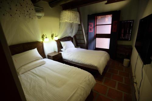 ein Schlafzimmer mit 2 Betten und einem TV in der Unterkunft Red Tomato B&B in Jinsha