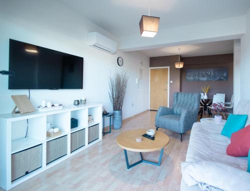 a living room with a couch and a tv at Maestro III Apartment in Larnaka