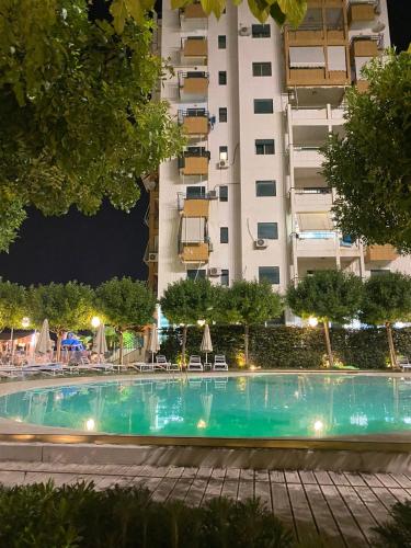 una piscina di fronte a un edificio di notte di Sunset Serenity Apartment a Durrës