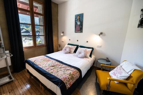 a bedroom with a bed and a yellow chair at Transhumance & cie, Auberge, Appartements & SPA in Bedous
