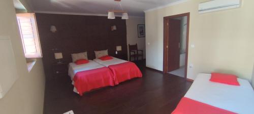 a bedroom with two beds with red and white sheets at Rilhadas Casas de Campo in Fafe