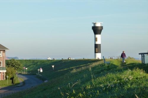 a man walking past a lighthouse on a hill at Ferienwohnung Faby in Hollern-Twielenfleth
