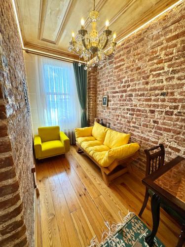 a living room with a yellow couch and a brick wall at İstanbul Eagle's Nest Boutique Hotel in Istanbul