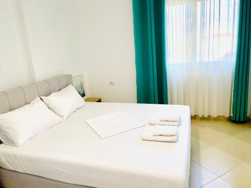 a bedroom with a white bed with towels on it at Divjaka Apartments 3 - City Center in Divjakë