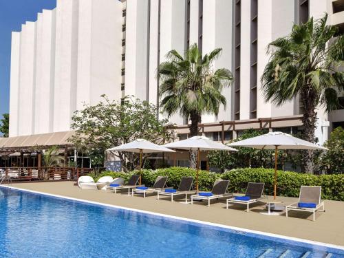 a hotel pool with lounge chairs and umbrellas at Novotel Dakar in Dakar
