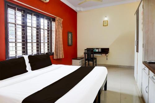 a bedroom with a white bed and red walls at Hotel O Varun Residency in Bengaluru