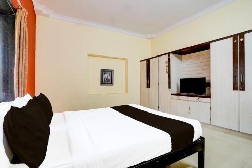 a bedroom with a white bed and a television at Hotel O Varun Residency in Bengaluru