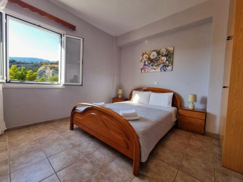 a bedroom with a bed and a large window at Maspali Apartments in Lixouri