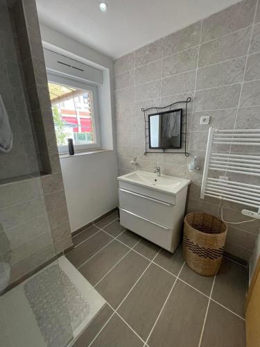 une salle de bain avec un lavabo et une télévision au mur dans l'établissement Apparemment T2 en centre ville, à Gournay-en-Bray