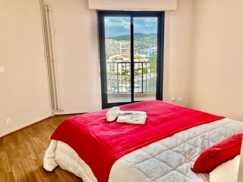 une chambre avec un lit avec une couverture rouge et une fenêtre dans l'établissement Les Masters YourHostHelper, à Mandelieu-la-Napoule