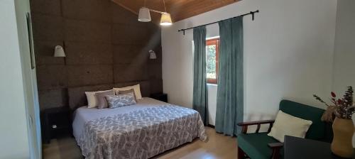 a bedroom with a bed and a window and a chair at Rilhadas Casas de Campo in Fafe