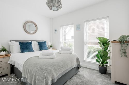 a white bedroom with a bed with blue pillows at StarHost Residences - Brand New 2 bed apartment in Newbury Centre in Newbury