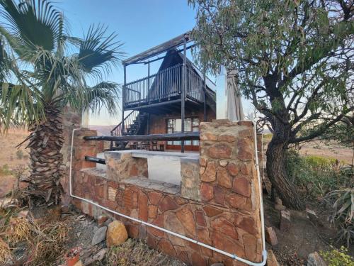 a house on top of a brick wall with a tree at Tonquani Bush Chalet in Rustenburg